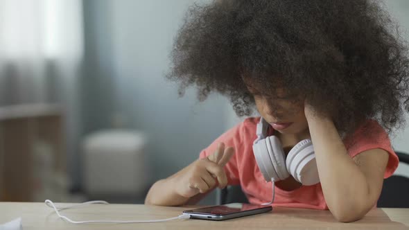 African American Girl Sitting Alone and Watching Movie on Smartphone, Gadget alt