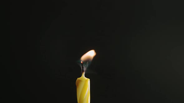 Single Big Yellow Candle Flame Lights and Extinguish Isolated on a Black Background Slow Motion alt