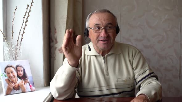 Smiling Senior Man Wear Earphones Wave to Camera Having Video Call on Laptop Happy Elderly Male in alt