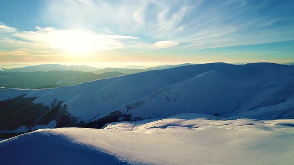 Flight over the snowy mountains illuminated by the evening sun alt