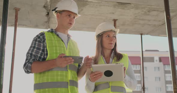 Building in Construction with a Female and a Male Engineers Using a Tablet and Mobile Phone to alt