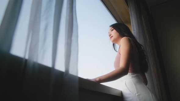 Happy attrative asian woman wearing casual cloth hand pull opening curtains alt