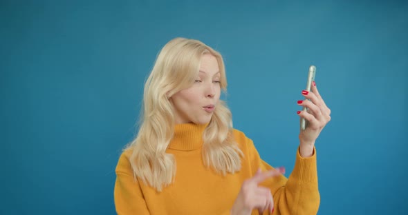 Happy Blonde Woman Looks Surprised Showing Green Screen Phone at Camera alt