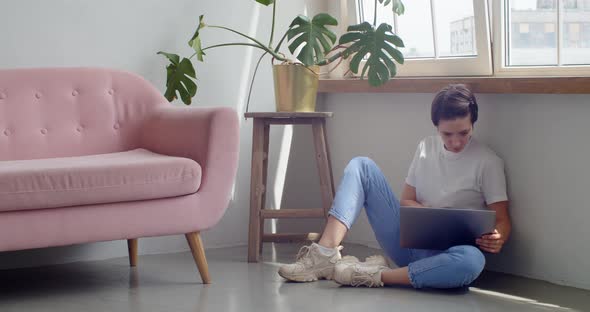 Stylish Girl in Jeans Sitting Indoors Working on Laptop on Floor Copy Space Text