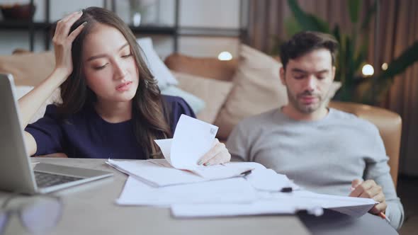 young asian caucasian couple checking bills,discussing planning budget together