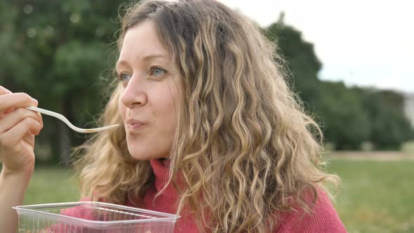 Woman Eating a Sweet Dessert with a Disposable Fork From a Plastic Container, Food Take-away in alt