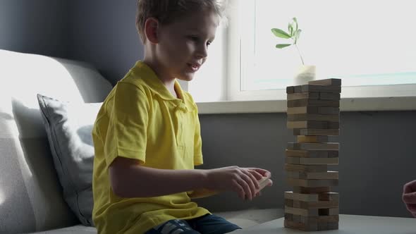 Father and Son is Playing in Board Game with Wooden Tower Together at Home