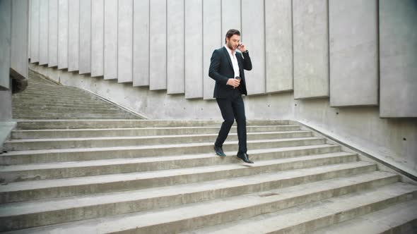 Business Man Running on Stairs in City. Male Employee Talking on Smartphone alt