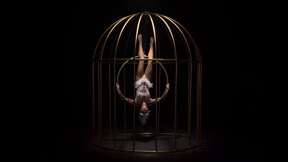 Gymnast Spinning on a Hoop in a Gold Cage. Black Background alt