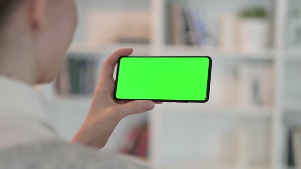 Rear View of Woman Doing Online Meeting on Smartphone with Chroma Key Screen alt
