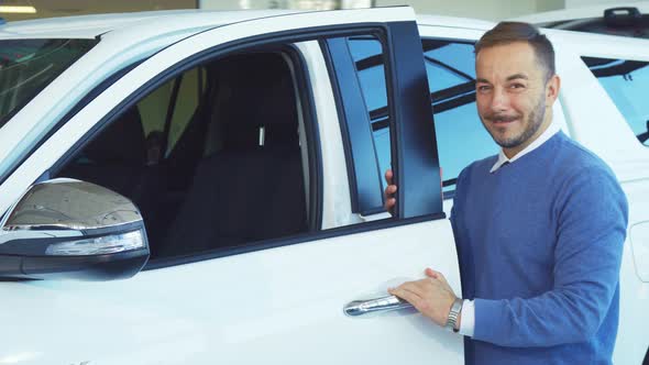 A Smiling Man Opens the Doors of His New Car