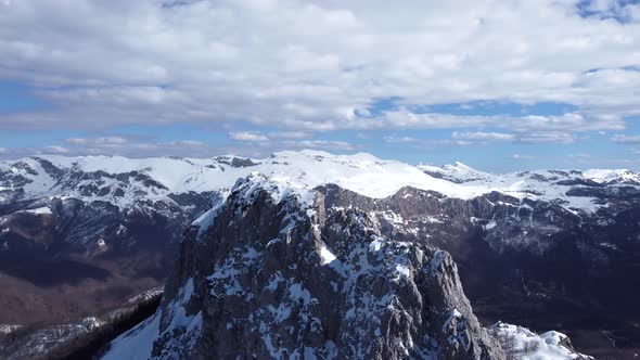 Aerial drone view of difficult access mountain peak for climbers during a winter sunny day.