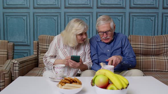 Senior Elderly Couple Grandfather Grandmother Looking on Mobile Phone Making Online Shopping alt