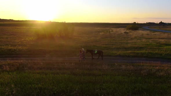 Two Women Lead a Horse on a Leash on Lectric Unicycles at Sunset alt