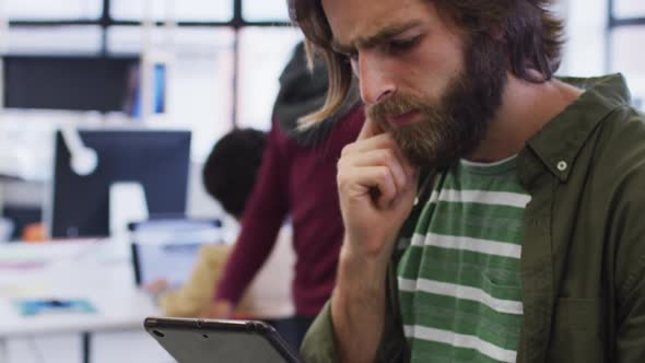 Caucasian businessman standing using a digital tablet in modern office alt