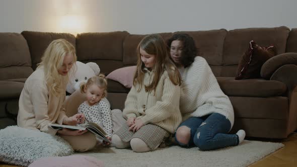 Mother Children Reading Book and Playing with Pets Sitting By Sofa at Home Interior Rbbro alt