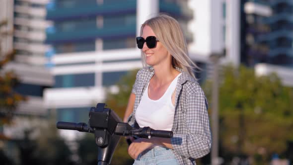 a woman uses app in her smartphone to rent electric scooter. alt