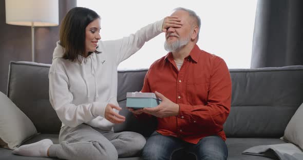 Adult Daughter Granddaughter Taking Red Gift Box to Senior Father Grandfather