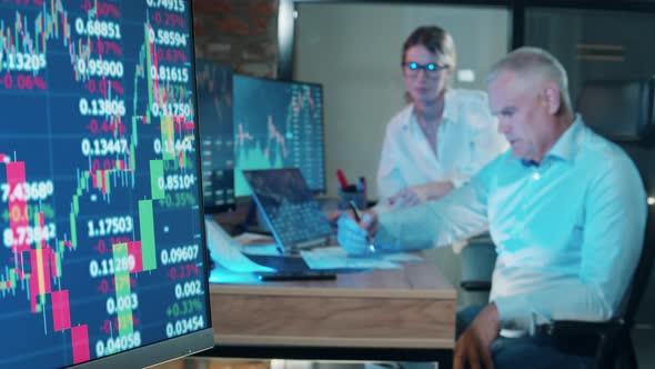 Monitors with Stock Data and Stockbrokers Talking Near Them alt