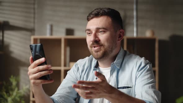 Happy Young Handsome Caucasian Man Looking at Smartphone Screen Holding Web Camera Video alt