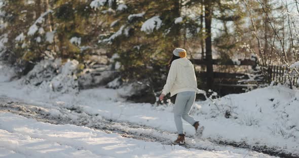 Woman in Winter Clothes Outdoors Against Snowy Mountains and Village alt