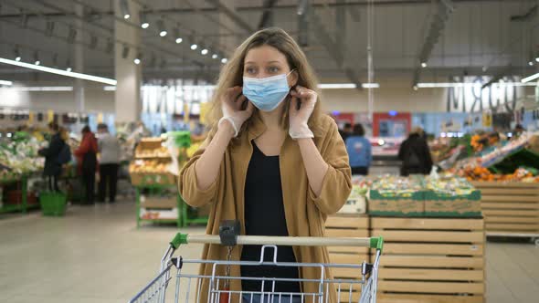 Girl Puts on a Medical Mask in a Supermarket To Protect Herself From the Coronavirus Pandemic alt