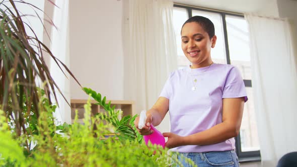 Woman Spraying Houseplant with Water at Home alt