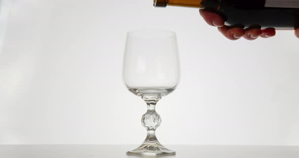 Close-up Shot. The Red Wine Is Pouring Into a Glass, White Background alt
