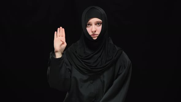 Middle Shot of Depressed Terrified Muslim Woman Raising Palm with Tuck Thumb Looking at Camera alt
