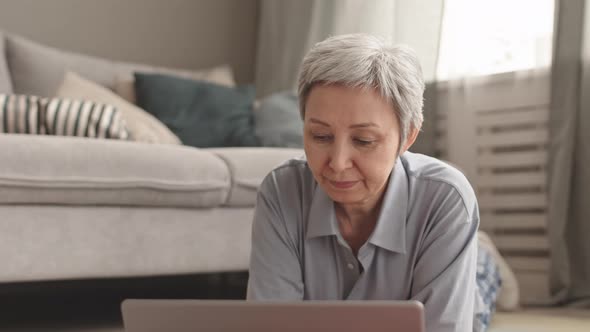 Senior Woman Drinking from Cup Lying alt