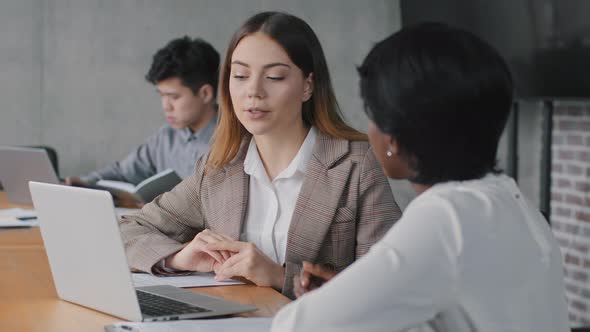 African and Caucasian Female Coworkers Discussing Startup Business Project Website Working Together alt