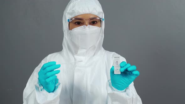 doctor in PPE suit holding Coronavirus(Covid-19) negative test result with Antigen Rapid Test kit alt