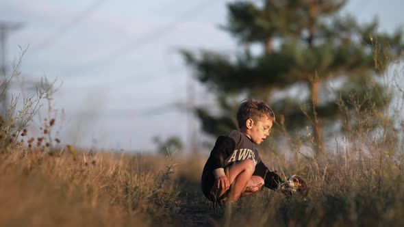 Cute Little Boy Playing with Tiny Beagle Puppy on Countryside Nature Background alt
