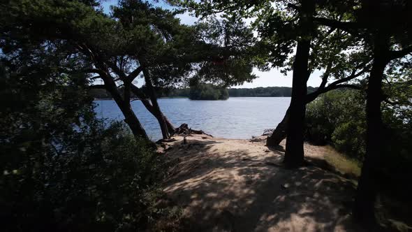 Forward aerial showing peninsula pathway ending in beach and continuing over pristine clear water of alt