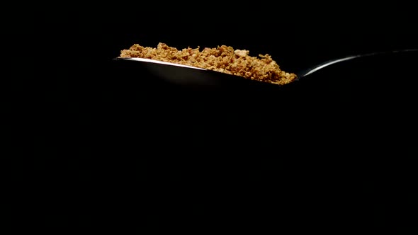 Bread Crumbs Falling From Spoon in Slow Motion Isolated on Black Background