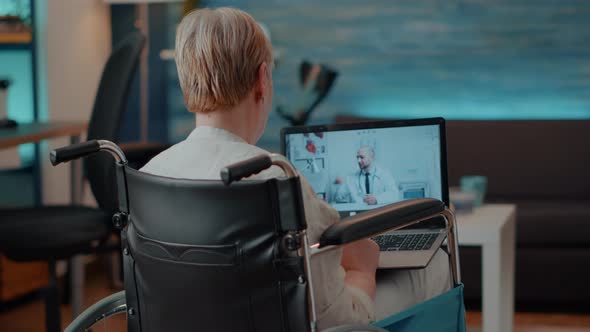 Retired Person in Wheelchair Using Videoconference Call alt
