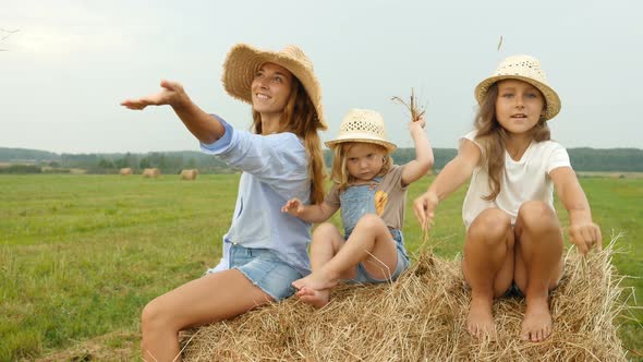 Mum and Two Little Cute Daughters Sit on the Haystack