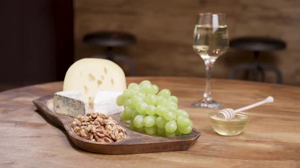 Cheese and Grapes on a Wooden Table with Honey, Walnuts and Wine alt