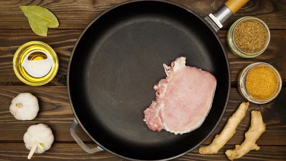 The cook puts raw meat steaks in a frying pan. Sliced pork meat in a cast iron skillet. Fry