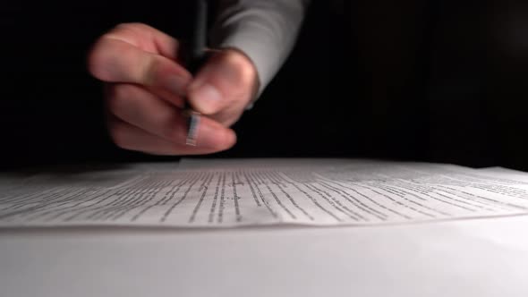 Man Fills On Documents With Pen Under Low Light At Home