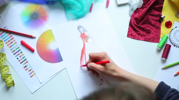 Fashion designer draws a sketch of women's clothing. alt