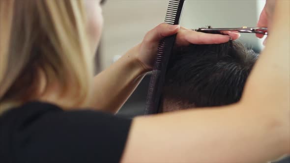Close Up Shot of the Hairdresser's Hands Who Cuts the Hair of Man in Barbershop alt