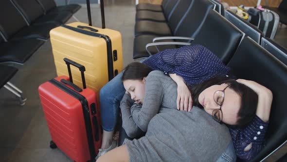 Woman with Daughter Teen Together Sleeping on Chairs in the Airport Waiting for Departure