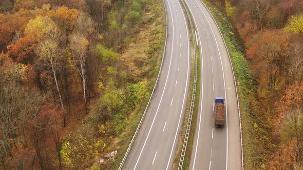 Truck Drives Into Distance on Freeway Amid Yellow Trees in Fall - Coming Into Shot alt