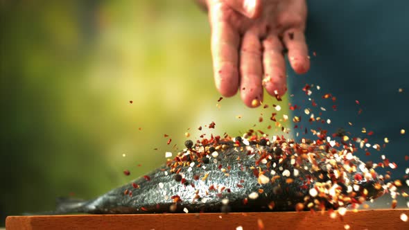 Male Chef Seasoning Fresh Dorado Fish With Pepper And Salt A Close Up Of Hand Sprinkling alt