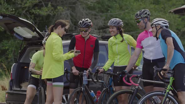 Group of cyclists look at photo on phone together.  Fully released for commercial use.