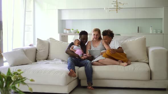 Mixed Race Family Watch Movie on Tablet Together on Sofa Spbd alt