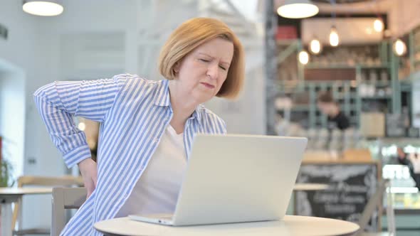 Creative Old Woman with Back Pain Using Laptop in Cafe alt