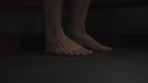 Dark Morning Shot of Man Feet on the Floor Near Bed alt