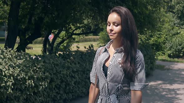 Wonderful Girl in Summer Dress with Stripes Walks in Park alt
